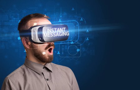 Téléchargez les photos : Homme d'affaires regardant à travers des lunettes de réalité virtuelle avec inscription INSTANT MESSAGING, concept de réseautage social - en image libre de droit