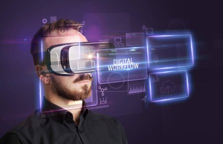 Téléchargez les photos : Homme d'affaires regardant à travers des lunettes de réalité virtuelle avec inscription DIGITAL WORKFLOW, nouveau concept technologique - en image libre de droit