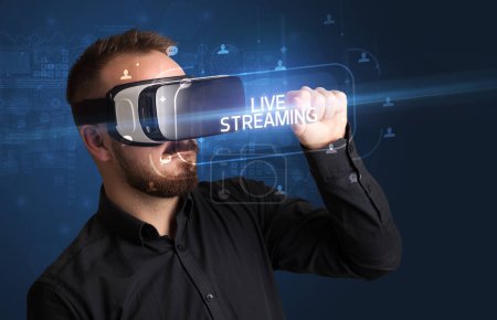 Téléchargez les photos : Homme d'affaires regardant à travers des lunettes de réalité virtuelle avec inscription LIVE STREAMING, concept de réseautage social - en image libre de droit