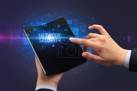 Téléchargez les photos : Homme d'affaires tenant un smartphone pliable avec inscription NETWORK SECURITY, concept de cybersécurité - en image libre de droit