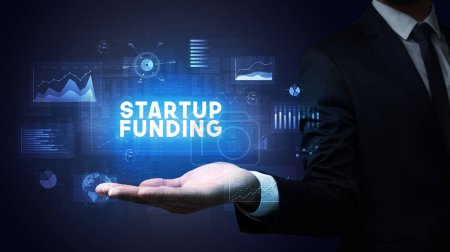 Hand of Businessman holding STARTUP FUNDING inscription, business success concept