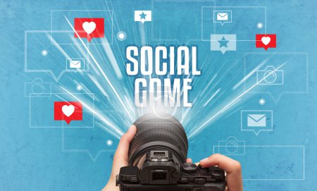 Primer plano de una mano tomando fotos con inscripción SOCIAL GAME, concepto de redes sociales