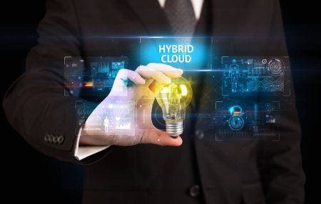 Empresario sosteniendo bombilla con inscripción HYBRID CLOUD, concepto de idea de seguridad en línea