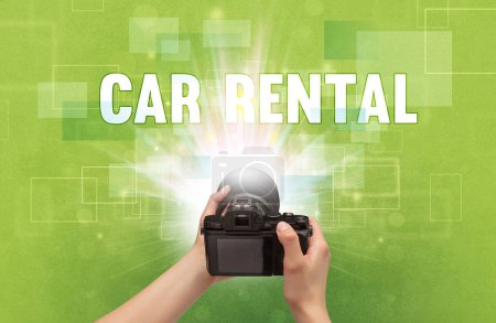 Photo for Close-up of a hand holding digital camera with CAR RENTAL inscription, traveling concept - Royalty Free Image