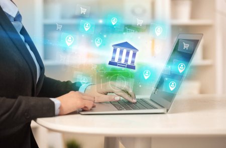 Foto de Empresario trabajando en el ordenador portátil con iconos bancarios que salen de ella, concepto de negocio exitoso - Imagen libre de derechos