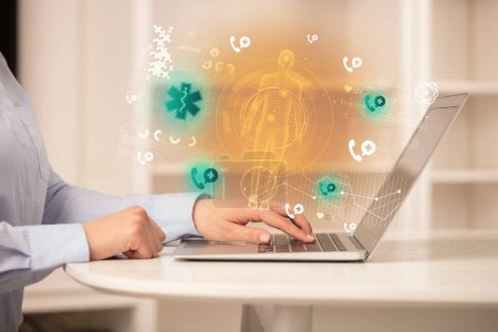 Téléchargez les photos : Médecin travaillant sur un ordinateur portable avec des icônes de pharmacie qui en sortent, concept de soins de santé - en image libre de droit