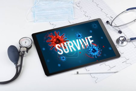Foto de Tablet PC y herramientas médicas en superficie blanca con inscripción SURVIVE, concepto pandémico - Imagen libre de derechos