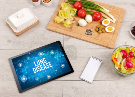 Téléchargez les photos : LUNG DISEASE concept en comprimé PC avec des aliments sains autour, vue du dessus - en image libre de droit