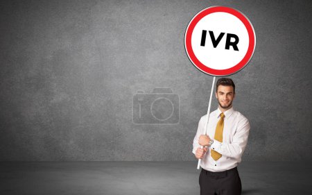 Téléchargez les photos : Jeune homme d'affaires holdig panneau de signalisation avec abréviation IVR, concept de solution technologique - en image libre de droit
