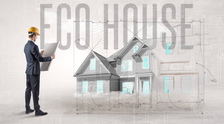 Téléchargez les photos : Jeune ingénieur tenant un plan avec inscription ECO HOUSE, concept de planification de la maison - en image libre de droit