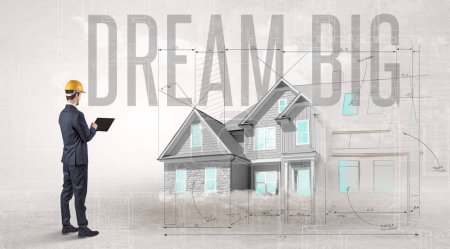 Young engineer holding blueprint with DREAM BIG inscription, house planning concept