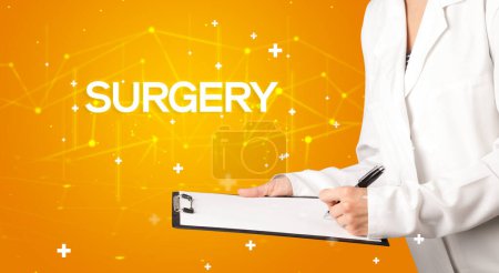 Photo for Doctor fills out medical record with SURGERY inscription, medical concept - Royalty Free Image