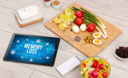 Téléchargez les photos : MEMORY LOSS concept en tablette pc avec des aliments sains autour, concept vue du dessus - en image libre de droit