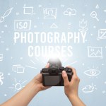 Hand taking picture with digital camera and PHOTOGRAPHY COURSES inscription, camera settings concept
