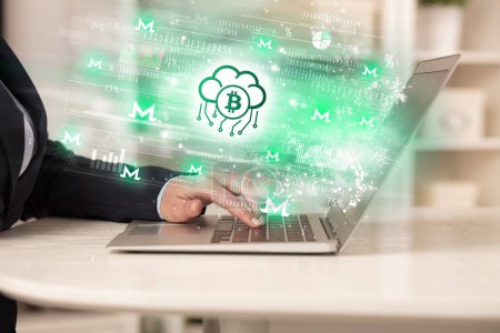 Photo for Young man watching stock market on laptop with bitcoin in cloud icons, forex concept - Royalty Free Image