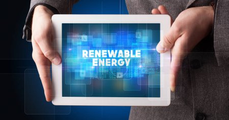 Photo for Young business person working on tablet and shows the inscription: RENEWABLE ENERGY - Royalty Free Image