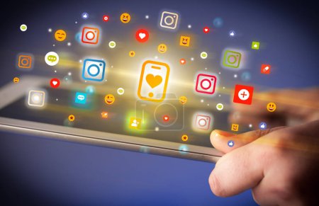 Téléchargez les photos : Gros plan d'une main à l'aide d'une tablette avec smartphone coloré avec des icônes cardiaques qui en ressortent, Concept de réseautage social - en image libre de droit