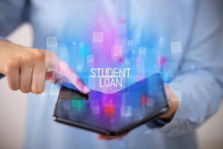 Young man holding a foldable smartphone with STUDENT LOAN inscription, educational concept