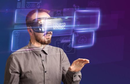 Téléchargez les photos : Homme d'affaires regardant à travers des lunettes de réalité virtuelle avec inscription CRYPTO MINING, nouveau concept technologique - en image libre de droit