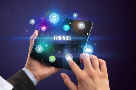 Téléchargez les photos : Homme d'affaires tenant un smartphone pliable avec inscription FRIENDS, concept de médias sociaux - en image libre de droit