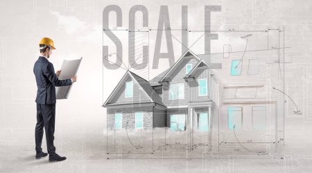 Foto de Joven ingeniero sosteniendo plano con inscripción SCALE, concepto de planificación de la casa - Imagen libre de derechos