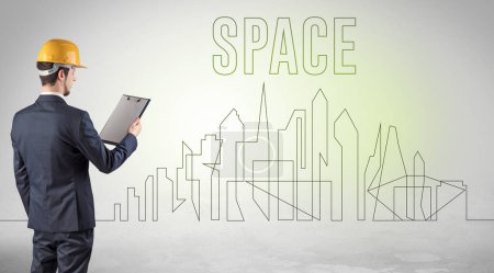 Téléchargez les photos : Homme d'affaires en casque rigide tenant un plan avec inscription SPACE, concept d'ingénierie et d'architecture - en image libre de droit