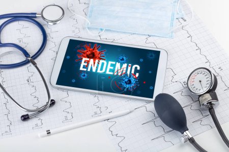 Téléchargez les photos : Tablette pc et outils médicaux sur surface blanche avec inscription ENDEMIC, concept pandémique - en image libre de droit