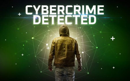 Téléchargez les photos : Mystérieux hacker avec inscription CYBERCRIME DETECTED, inscription de concept d'attaque en ligne, concept de sécurité en ligne - en image libre de droit