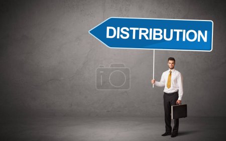 Young business person in casual holding road sign with DISTRIBUTION inscription, new business direction concept
