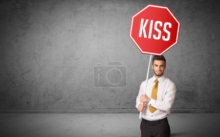 Photo for Young business person holding road sign with KISS inscription, new rules concept - Royalty Free Image