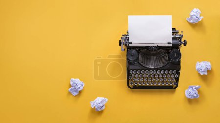 Téléchargez les photos : Vintage machine à écrire et papiers froissés sur fond jaune avec espace de copie - en image libre de droit