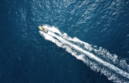 Téléchargez les photos : Vue en grand angle d'un bateau à moteur accélérant sur l'océan avec espace de copie - en image libre de droit