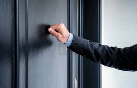 Close up of young man knocking on the door with copy space