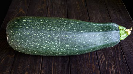 Photo for Vegetable marrow zucchini on vintage wooden table. Photography of one big fresh squash isolated on dark planks. Theme of zucchini, organic food, nature, summer, farm. - Royalty Free Image