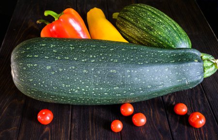 Photo for Vegetable marrow zucchini, sweet pepper and tomatoes on dark background. Photography of fresh squash on old wooden table. Theme of zucchini, organic food, nature. - Royalty Free Image