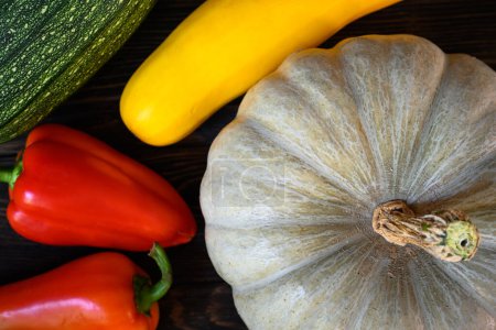 Photo for Pumpkin and vegetable marrow on dark wooden table, top view. Still life of organic food, sweet red pepper and zucchini, flat lay. Harvest, vegetable, thanksgiving, nature, farm and squash concept. - Royalty Free Image