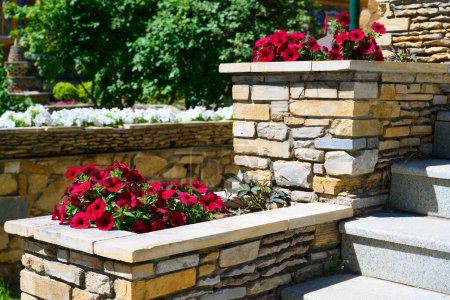 Landschaftspflege auf Haustreppe mit Blumenbeeten, häusliche Landschaftsgestaltung. Hochwertiger Garten im Sommer. Blumen und Pflanzen auf schönen floralen Terrassen im Garten.