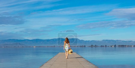 Foto de Mujer caminando sobre muelle de madera (Cataluña, Delta del Ebro, España)) - Imagen libre de derechos