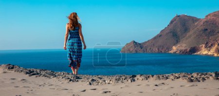 Photo for Woman with blue dress looking at panoramic coastline view of natural park, cabo de gata- Almeria,  Andalusia in Spain - Royalty Free Image
