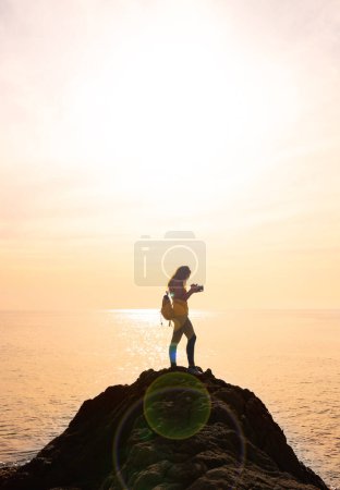 Photo for Silhouette of woman photographer taking photo on sunset sea - Royalty Free Image