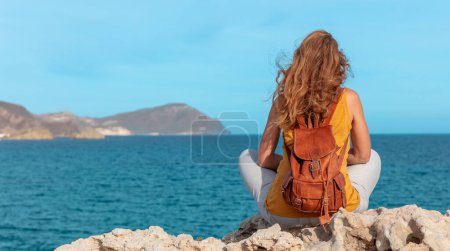 Photo for Woman sitting on rock enjoying sea view- travel,  freedom,  yoga concept - Royalty Free Image