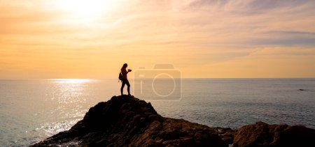 Photo for Silhouettte of woman photographer taking photo on sunset at the sea - Royalty Free Image