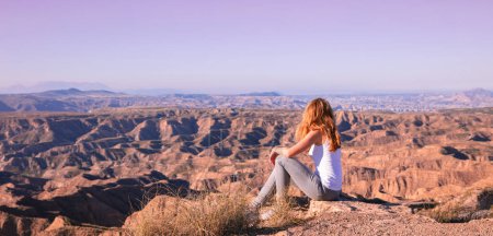 Foto de Woman sitting and looking at sunset Gorafe desert in Spain - Imagen libre de derechos