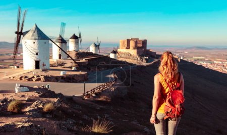 Foto de Woman tourist looking at windmills with castle, Consuegra, Castile-La Mancha, Spain - Imagen libre de derechos