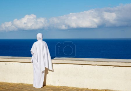 Photo for Muslim woman with white hijab looking at the sea- Morocco in Africa - Royalty Free Image