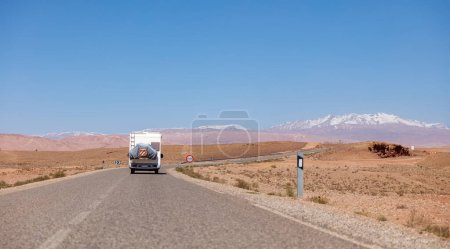 Photo for Road trip in Morocco- Asphalt road with driving motor home and mountain atlas in the background - Royalty Free Image