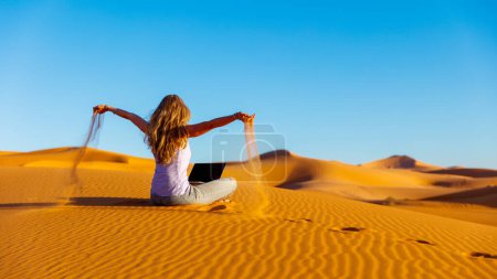 Téléchargez les photos : Femme à travers le sable dans le désert du Sahara avec ordinateur Freelancer, pause emploi, concept de stratégie d'entreprise - en image libre de droit