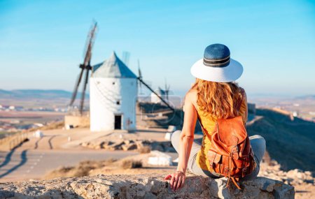 Téléchargez les photos : Vue arrière femme posant contre les moulins à vent dans la ville de Consuegra. Espagne - en image libre de droit