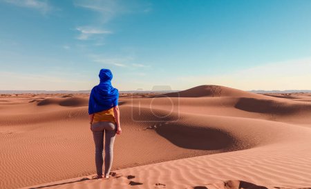 Foto de Mujer posando con turbante azul mirando panorama desierto arena duna paisaje - Imagen libre de derechos