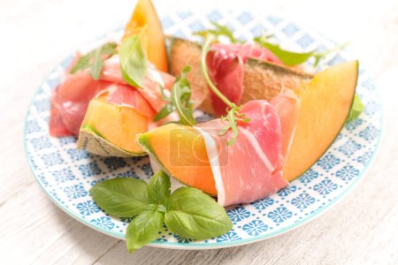 Photo for Sliced melon with ham and basil leaves - Royalty Free Image